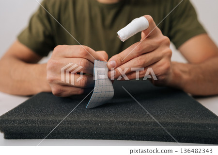 Male hands holding kinesiology tape, providing support and pain relief for muscle injury or joint problems, showcasing sports medicine and physiotherapy treatment concept. Male hands holding kinesiology tape, providing support and pain relief for muscle injury or joint problems, showcasing sports medicine and physiotherapy treatment concept. 136482343