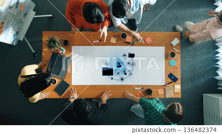 Group of Diverse Professionals Collaborating on Project in Modern Office with Laptop, Tablets, and Post-It Notes Spreading Ideas and Creativity Trope 136482374