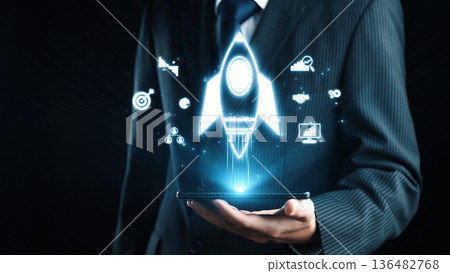 Businessman in Suit Holding Smartphone with Rocket Icon and Technology Symbols for Startup Growth and Innovation Concept. Qubit Businessman in Suit Holding Smartphone with Rocket Icon and Technology Symbols for Startup Growth and Innovation Concept. Qubit 136482768