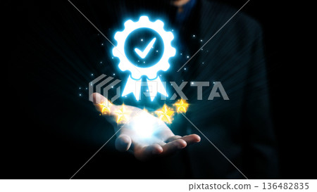 Glowing Badge of Approval in Hand with Stars and Light Effects Signifying Quality and Achievement in Dark Background. Qubit Glowing Badge of Approval in Hand with Stars and Light Effects Signifying Quality and Achievement in Dark Background. Qubit 136482835