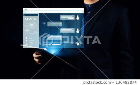 Business professional interacting with an innovative artificial intelligence chat interface while holding a digital tablet in a dark environment. Qubit Business professional interacting with an innovative artificial intelligence chat interface while holding a digital tablet in a dark environment. Qubit 136482874