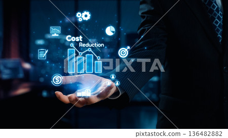 Businessman Presenting Concepts of Cost Reduction with Financial Graphs and Innovative Technology in Office Environment at Night. Qubit Businessman Presenting Concepts of Cost Reduction with Financial Graphs and Innovative Technology in Office Environment at Night. Qubit 136482882