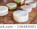 Natural handmade artisan round soap bars displayed on a rustic wooden table. Organic skincare products with minimalist design. 136483001