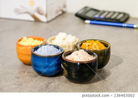 Colorful natural cosmetic ingredients in small ceramic bowls on a table. 136483002