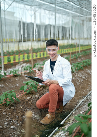 Researchers man holding paper chart checking the progress and growth of plants. Researchers man holding paper chart checking the progress and growth of plants. 136483520