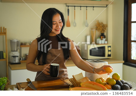 Smiling woman preparing healthy breakfast in a warm kitchen Smiling woman preparing healthy breakfast in a warm kitchen 136483554
