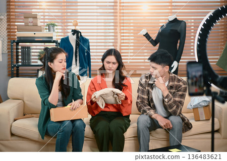 SME team facing product issue during live streaming, reviewing clothing quality and discussing problem solving at home office SME team facing product issue during live streaming, reviewing clothing quality and discussing problem solving at home office 136483621