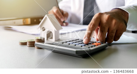 Close-up image of an Asian businessman's hands using a calculator and pen for financial accounting and budget planning. Strategic office workspace concepts for tax calculations, banking, investment Close-up image of an Asian businessman's hands using a calculator and pen for financial accounting and budget planning. Strategic office workspace concepts for tax calculations, banking, investment 136483668