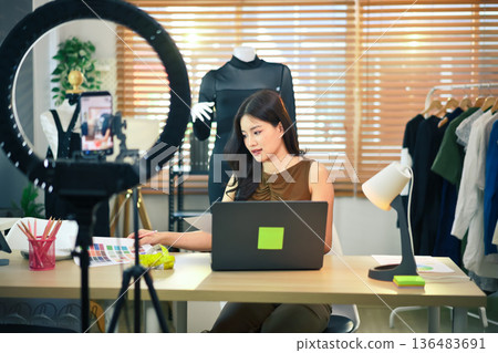 SME business asian woman using laptop and recording video or live streaming for sell fashion dress 136483691