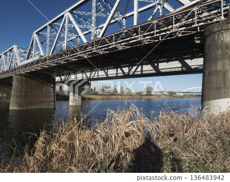 A powerful composition looking up at the Tama River Bridge, the winter riverbed, and the truss iron bridge shining against the blue sky 136483942