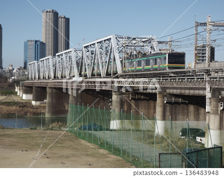 JR East's E233 series train crossing the Tamagawa Bridge and a group of tower apartment buildings in Kawasaki 136483948