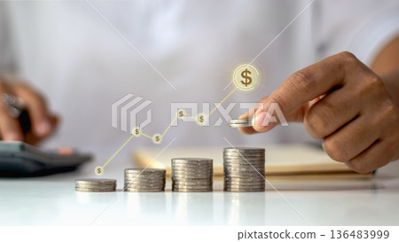 Businessman hand stacking coins with growing financial graph and dollar icons, concept of investment, profit, business success, and money savings growth. Businessman hand stacking coins with growing financial graph and dollar icons, concept of investment, profit, business success, and money savings growth. 136483999
