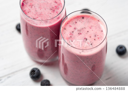 Two glasses of berry smoothie with chia and fresh berries on a white wooden table Two glasses of berry smoothie with chia and fresh berries on a white wooden table 136484888