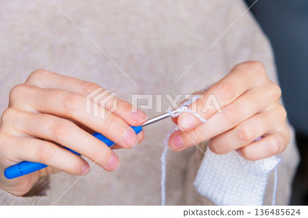Young happy woman crocheting at home relaxing and meditating Young happy woman crocheting at home relaxing and meditating 136485624