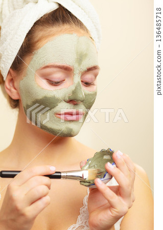 Woman applying with brush clay mud mask to her face 136485718