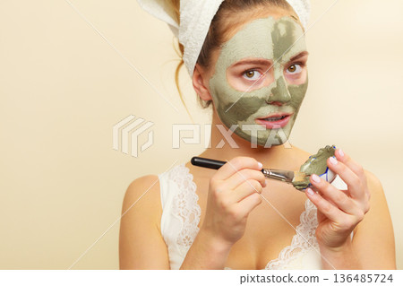Woman applying with brush clay mud mask to her face Woman applying with brush clay mud mask to her face 136485724