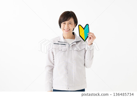 A woman in work clothes holding a beginner's mark A woman in work clothes holding a beginner's mark 136485734