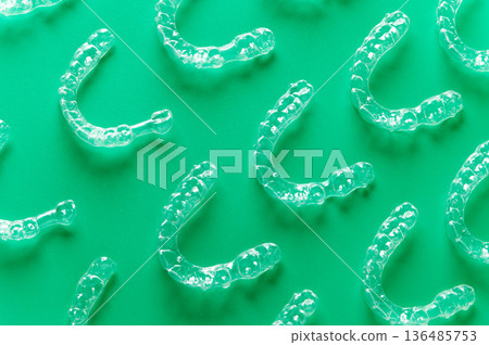 Clear aligners and braces on a colored background. Many clear hedgehog braces on a colored background. Dental background. Technological dentistry. Clear aligners and braces on a colored background. Many clear hedgehog braces on a colored background. Dental background. Technological dentistry. 136485753