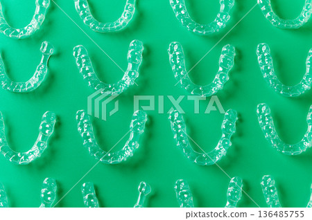 Clear aligners and braces on a colored background. Many clear hedgehog braces on a colored background. Dental background. Technological dentistry. Clear aligners and braces on a colored background. Many clear hedgehog braces on a colored background. Dental background. Technological dentistry. 136485755