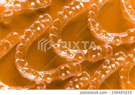 Extreme macro close-up of clear braces. Multiple aligners against a colored background, close-up with a shallow depth of field. 136485819
