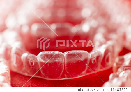 Extreme macro close-up of clear braces. Multiple aligners against a colored background, close-up with a shallow depth of field. 136485821