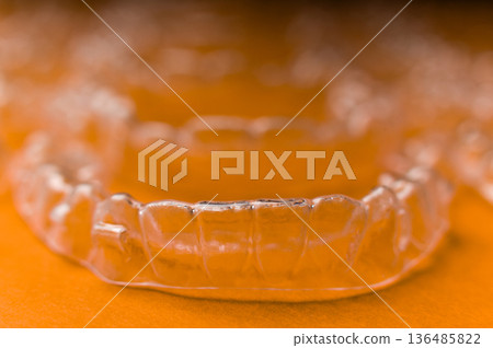 Extreme macro close-up of clear braces. Multiple aligners against a colored background, close-up with a shallow depth of field. 136485822