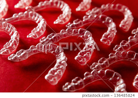 Dental background: many clear braces and aligners lie textured on a colored background. Dental technology 136485824