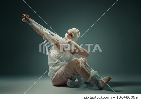 Conceptual art of a person wrapped in bandages struggling to break free from confinement. Conceptual art of a person wrapped in bandages struggling to break free from confinement. 136486069