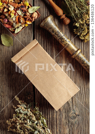 Brown paper bag and bundles of dried medicinal herbs on an old wooden table. Brown paper bag and bundles of dried medicinal herbs on an old wooden table. 136486120