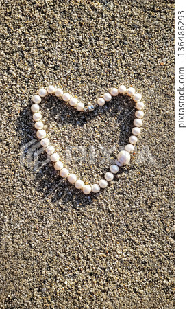 Concept of love and health. Heart shape made from a string of beads on sandy ground during daytime inviting thoughts of love and connection 136486293