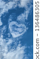 Clouds in the sky form a heart shape during a bright day, symbolizing love and connection in a serene atmosphere 136486305