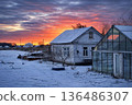 Cold Winter Countryside with Snowy Houses Under Dramatic Evening Sky 136486307