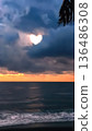 Heart shape appears in clouds over ocean during sunset near shore with waves crashing, creating a scene of natural beauty and connection 136486308