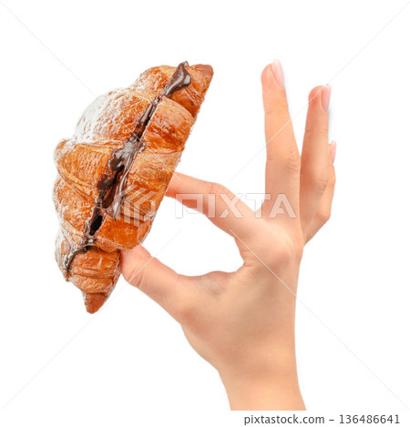 Chocolate filled croissant with powdered sugar held in female hand isolated on white 136486641