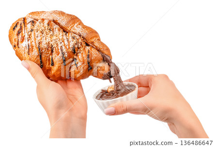 Croissant dipped in chocolate spread in female hands isolated on white Croissant dipped in chocolate spread in female hands isolated on white 136486647