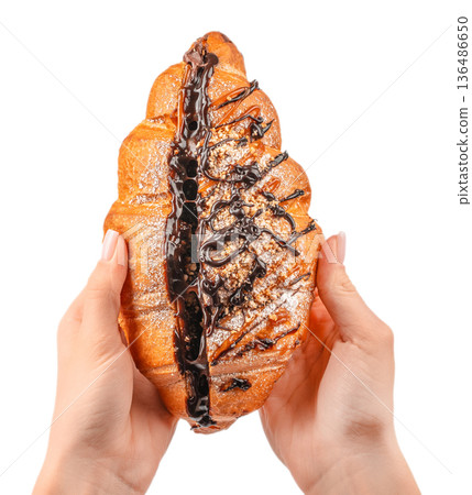 Large chocolate and caramel stuffed croissant with drizzle held in female hands isolated on white Large chocolate and caramel stuffed croissant with drizzle held in female hands isolated on white 136486650