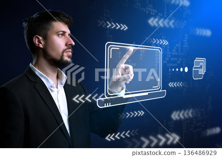 Man interacts with holographic laptop display in modern tech environment 136486929