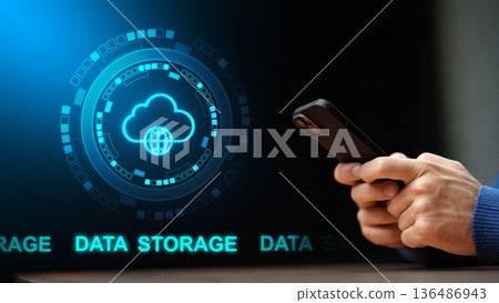 Person holds smartphone while looking at cloud data storage graphic on a screen 136486943