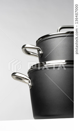 Nice black cooking pots stacked on a white shelf in a modern kitchen setting Nice black cooking pots stacked on a white shelf in a modern kitchen setting 136487000