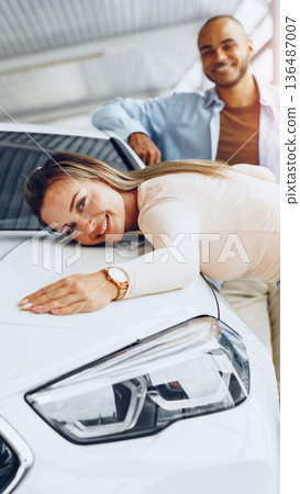 Couple celebrates new car while posing at dealership in bright indoor setting 136487007