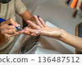 Manicure process with milling cutter at a salon showing a woman hands being treated in a professional setting during daylight hours 136487512