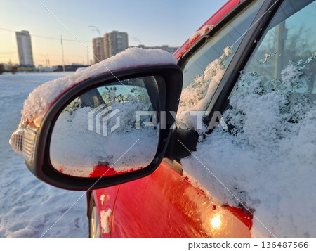 Snow clings to the side mirror of the red car Snow clings to the side mirror of the red car 136487566