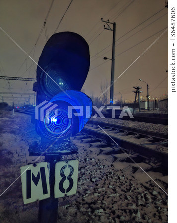 Railway traffic light with blue signal. Night and snow on the rails 136487606
