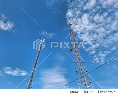 Cell towers against blue sky. Two cell towers on blue background 136487607