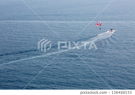Aerial view of parasailing activity over open sea. Aerial view of parasailing activity over open sea. 136488533