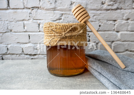 Honey jar with honeycomb and wood spoon stay on the stone table with napkin. Honey jar with honeycomb and wood spoon stay on the stone table with napkin. 136488645