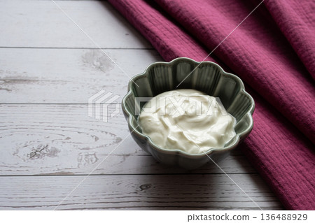 Natural white greek yogurt in porcelain green plate on the wood table with burgundy napkin for healthy breakfast. Food concept. Space for text. 136488929