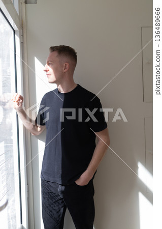 Young man contemplating while looking out window Young man contemplating while looking out window 136489666