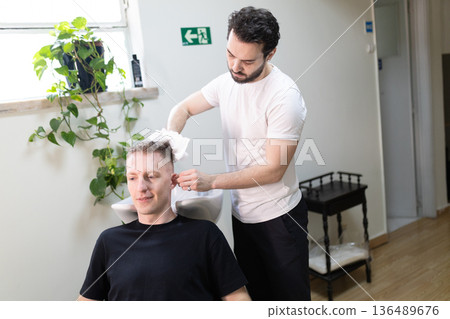 Hairdresser drying client's hair after washing in salon 136489676