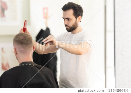 Barber cutting client's hair in salon Barber cutting client's hair in salon 136489684